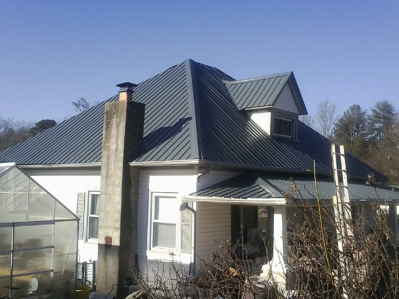 Dark blue standing seam metal roof on a white farmhouse with dormer — Slate & Tile Roof Repair by Roofing Brothers in Smallwood