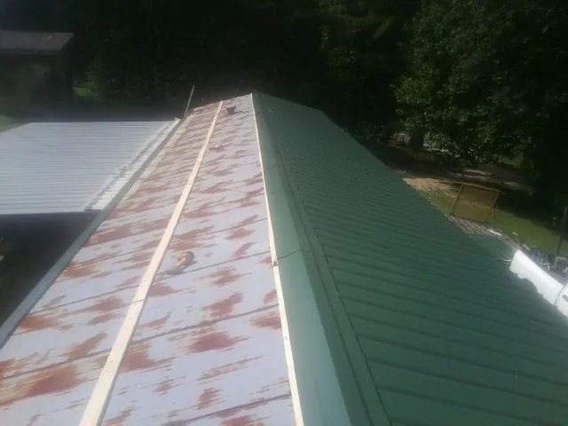 Old rusted panels beside newly installed green metal roofing — Wind Damage Roof Repair by Roofing Brothers in Smallwood