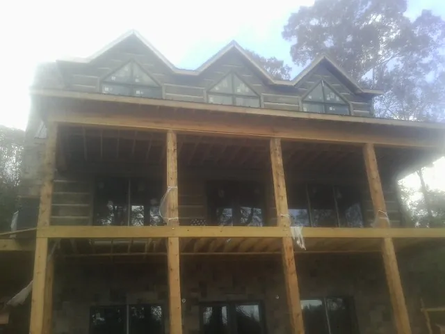 Dormers and porch framing on a large log home under construction — Roof Coating work by our crew in Smallwood
