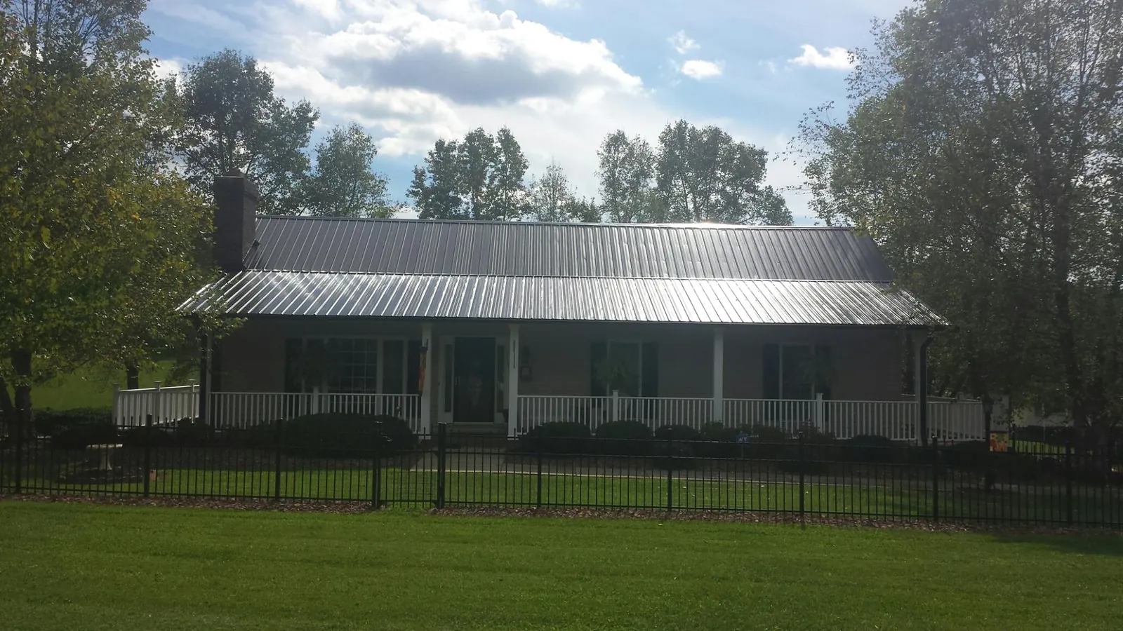 Gray metal roof on a brick ranch with a full width front porch — Gutter Guard Installation work by our crew in Smallwood
