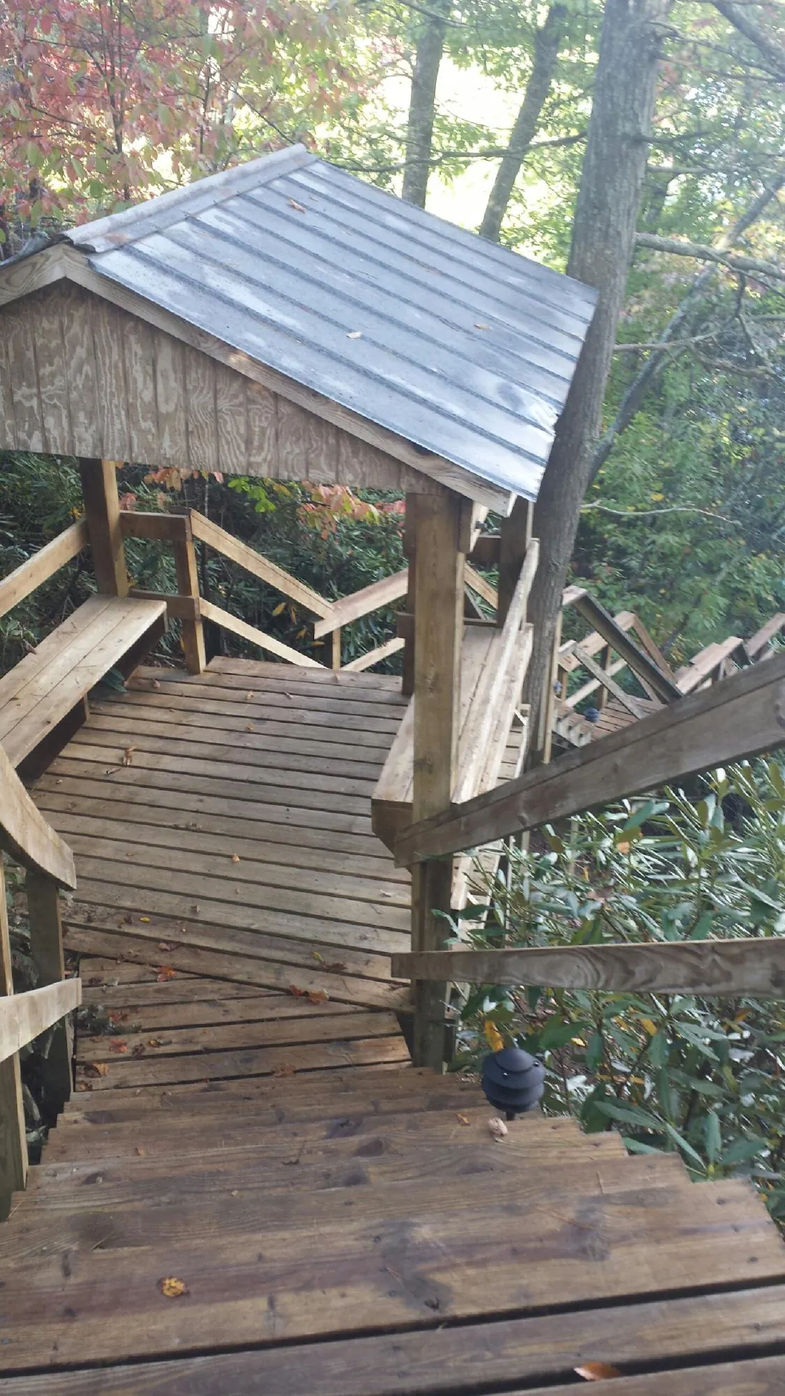 Metal roofed shelter over wooden steps on a wooded walkway — Skylight Repair & Installation work by our crew in Smallwood