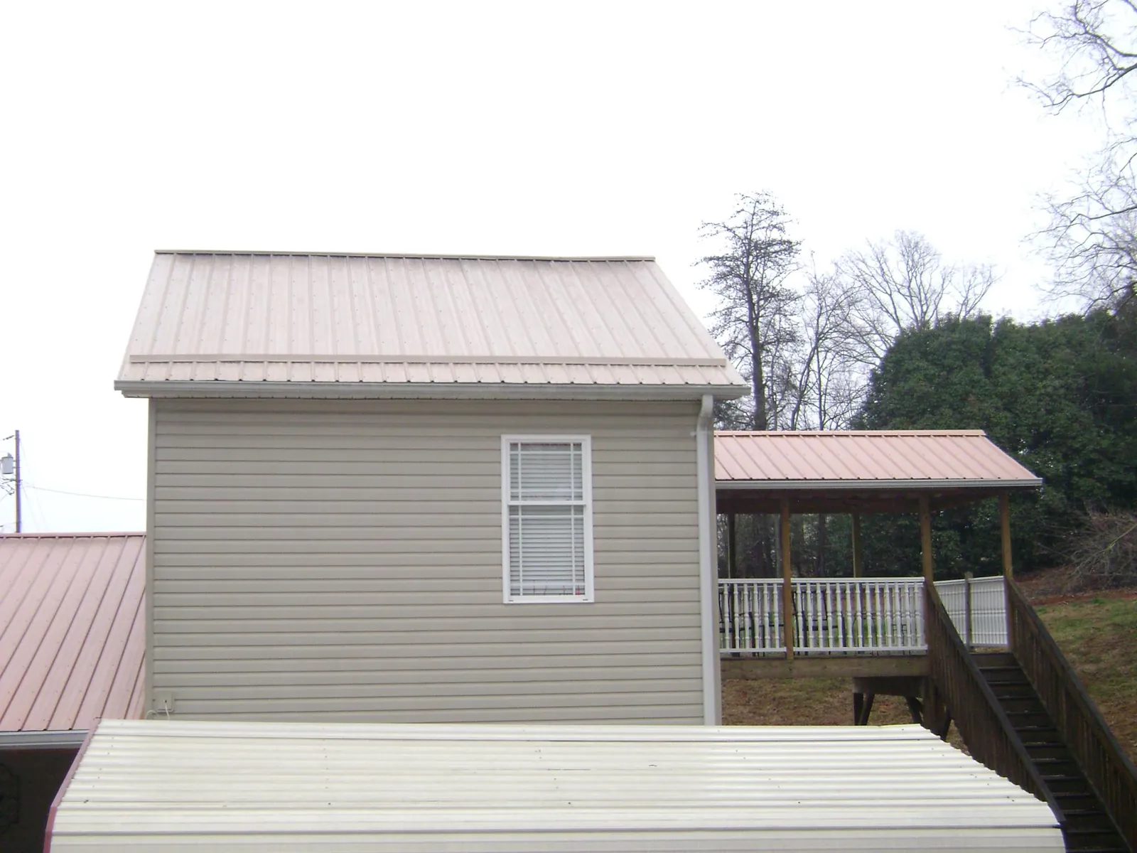 Tan metal roofs on a two story addition and attached porch, from a Roof Replacement job in Smallwood