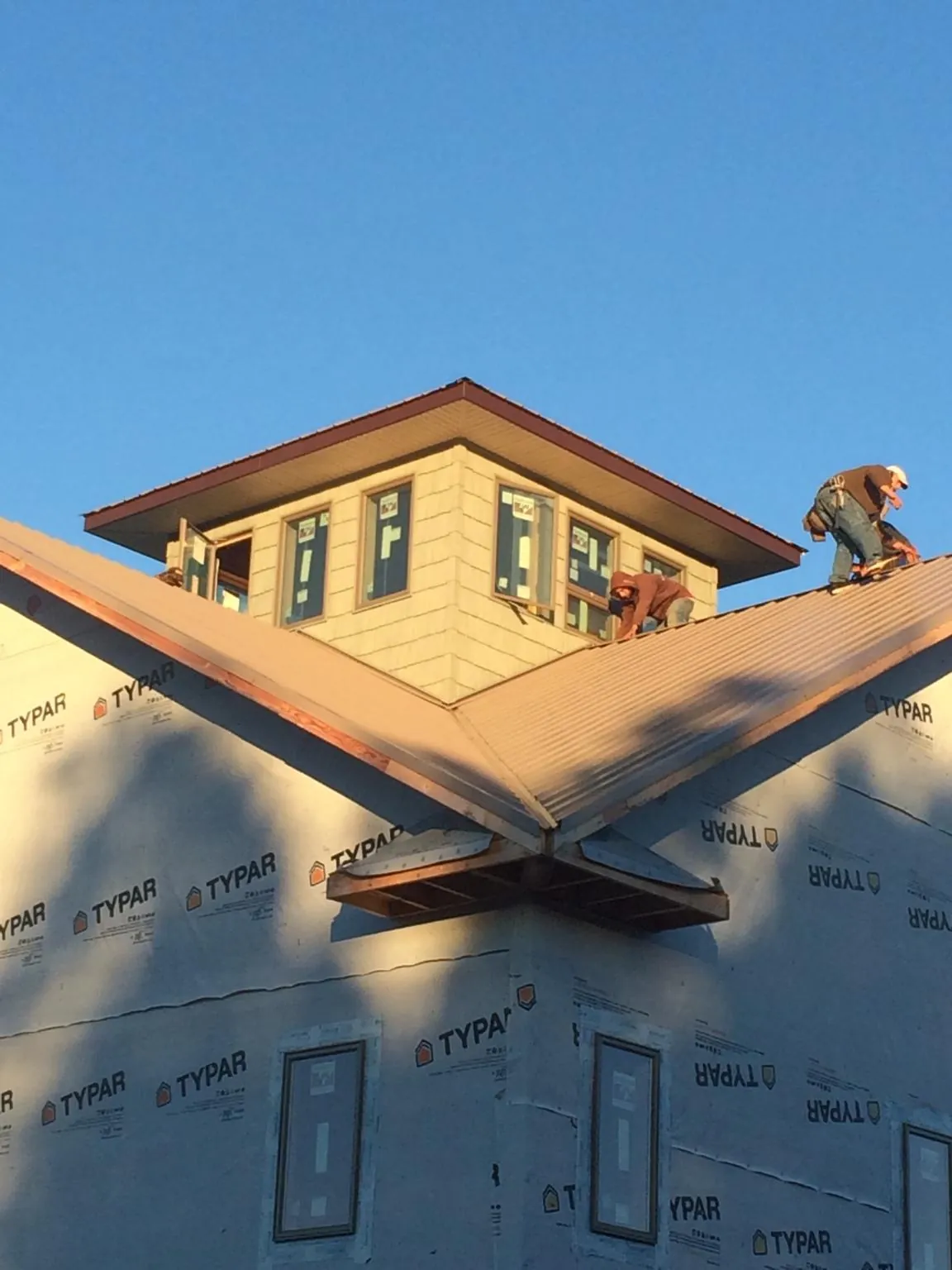 Roofers working around a rooftop cupola on a new metal roof at sunset — Roof Waterproofing in Smallwood by Roofing Brothers